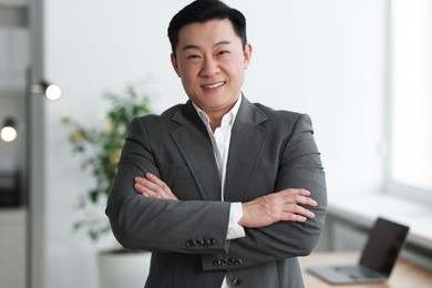 Photo of Portrait of smiling businessman with crossed arms in office