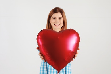 Photo of Portrait of woman with heart shaped balloon on light background