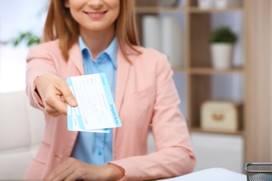 Photo of Female consultant holding tickets in travel agency, closeup. Space for text