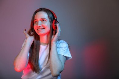 Photo of Portrait of beautiful woman with headphones on color background, space for text