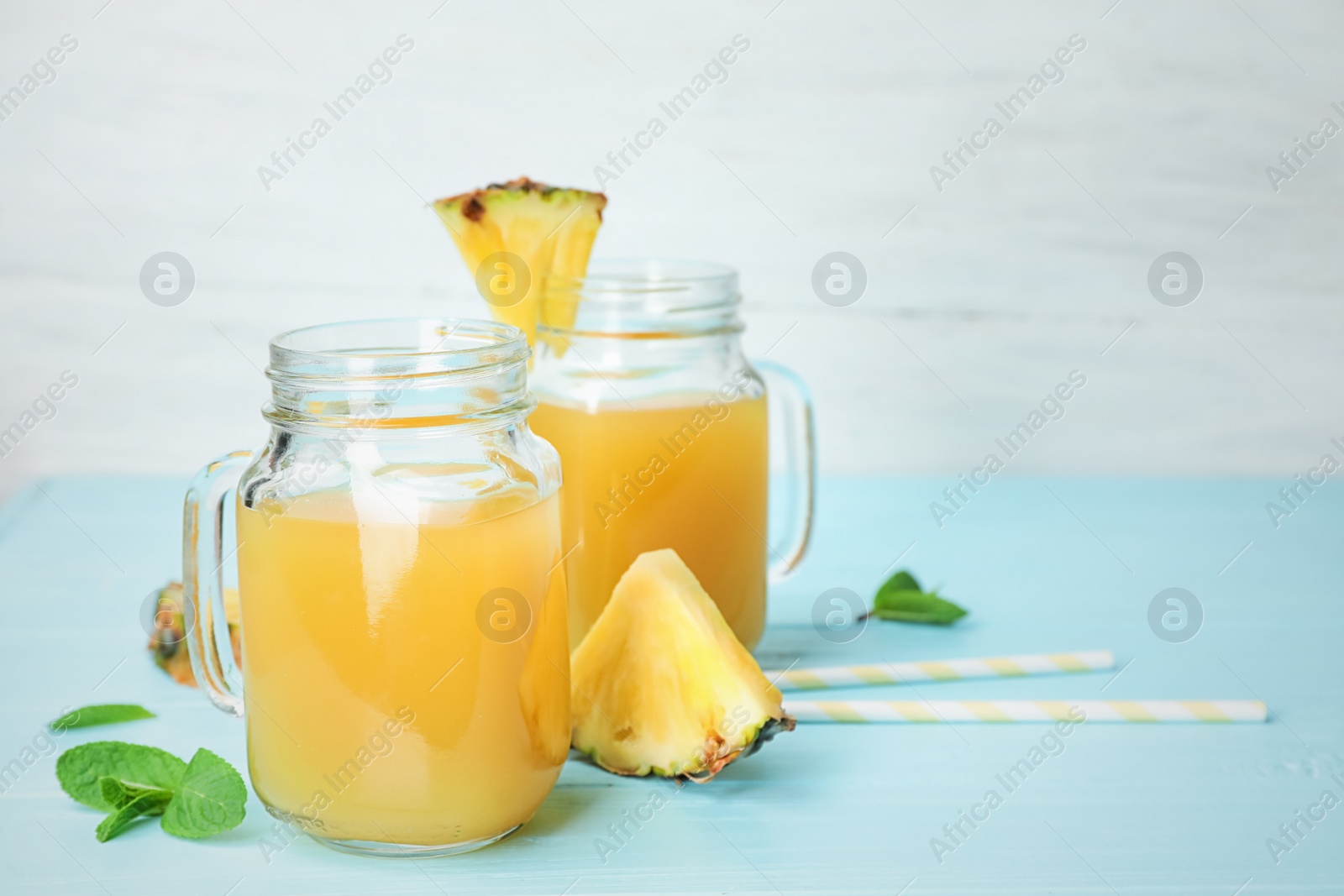 Photo of Mason jars with delicious pineapple juice on table