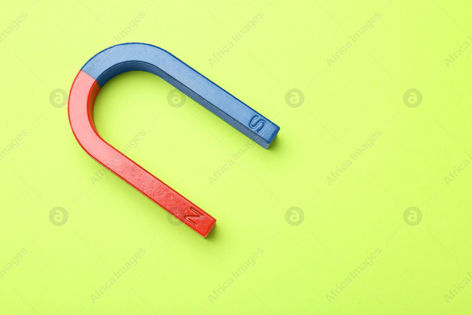 Photo of Red and blue horseshoe magnet on color background, top view with space for text