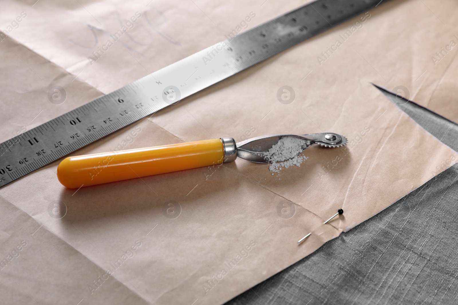 Photo of Tracing wheel and ruler with sewing pattern on fabric, closeup