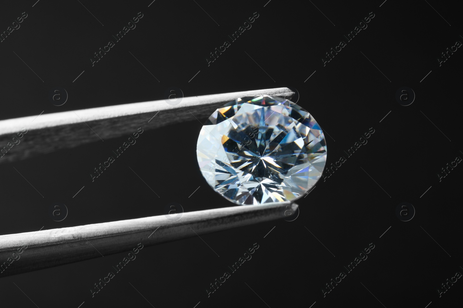 Photo of Tweezers with beautiful shiny diamond on black background, closeup