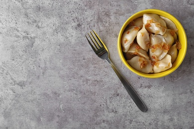 Delicious cooked dumplings with fried onion on grey table, flat lay. Space for text