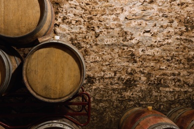 Photo of Wooden wine barrels near stone wall with space for text