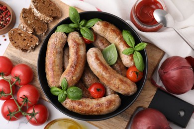 Photo of Flat lay composition with tasty homemade sausages, basil leaves and tomatoes in bowl on table