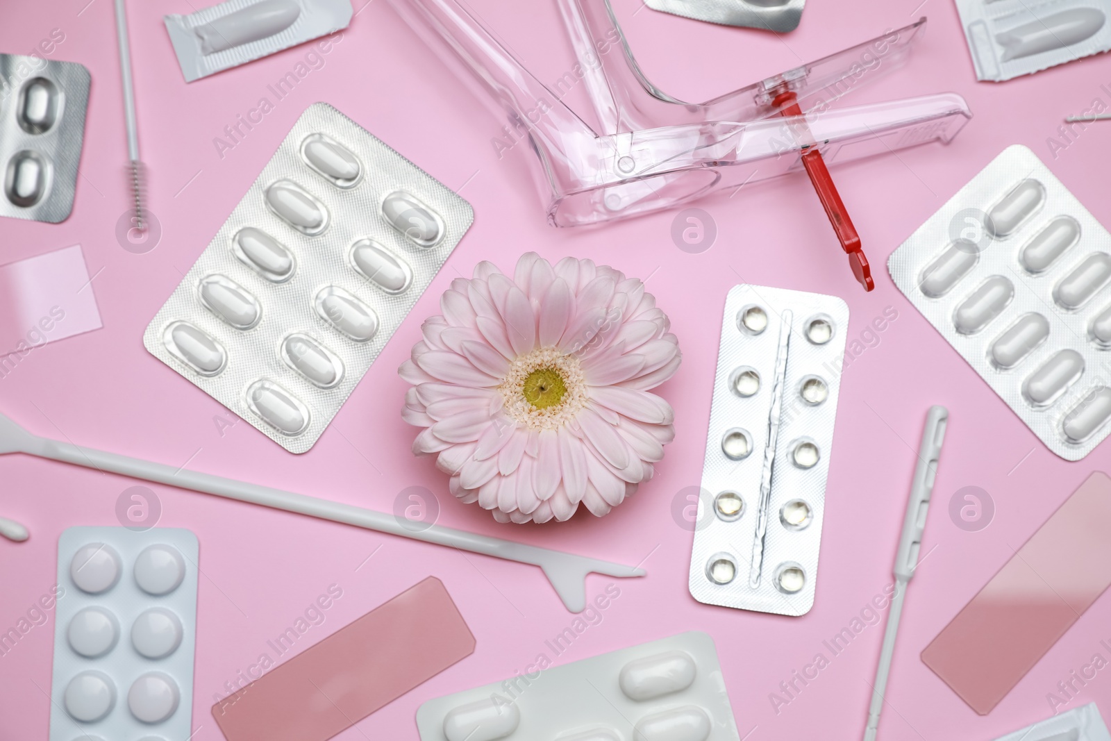 Photo of Many gynecological tools, pills and gerbera flower on pink background, flat lay