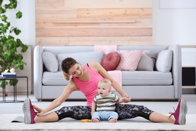 Photo of Young sportive woman doing exercise with her son at home. Fitness training