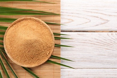 Photo of Coconut sugar, palm leaves and bamboo mat on wooden rustic table, top view. Space for text