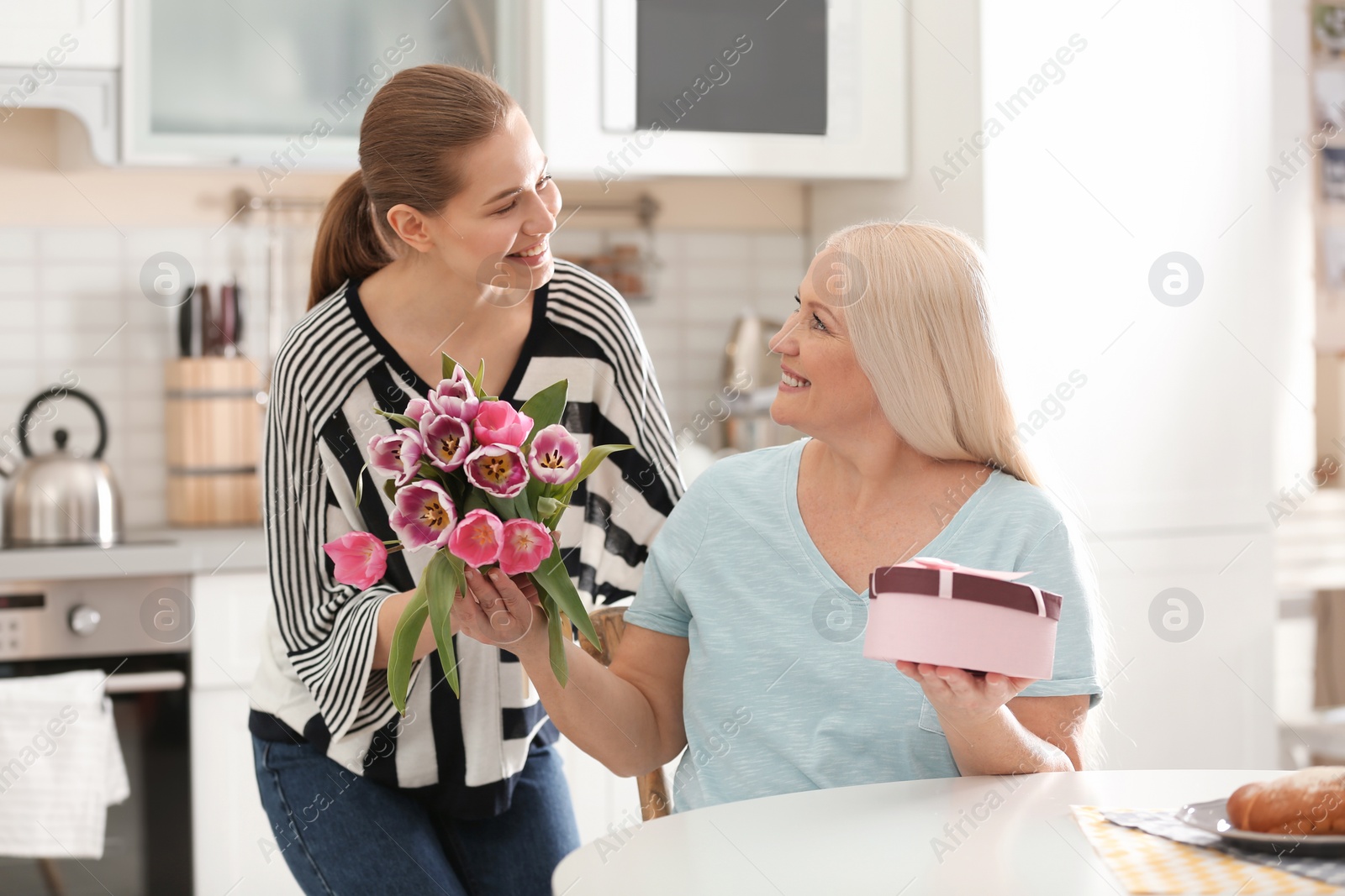 Photo of Daughter congratulating happy mature woman on Mother's Day at home