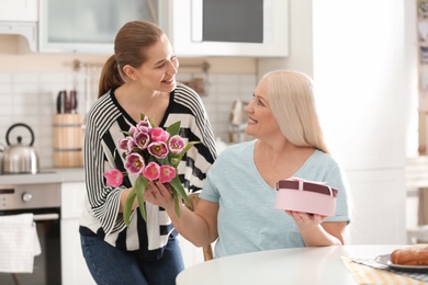 Photo of Daughter congratulating happy mature woman on Mother's Day at home