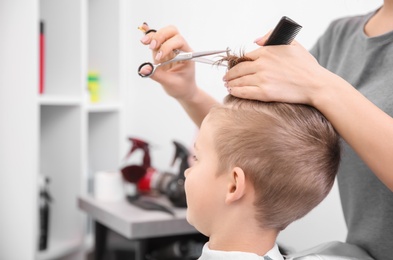 Photo of Professional female hairdresser working with little boy in salon