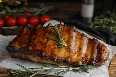 Photo of Tasty grilled ribs with rosemary on wooden table