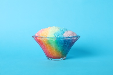 Photo of Rainbow shaving ice in glass dessert bowl on light blue background