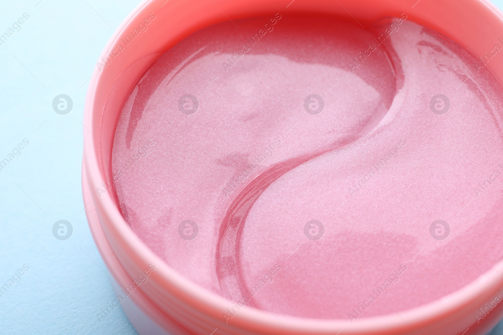 Photo of Under eye patches in jar on light blue background, closeup. Cosmetic product