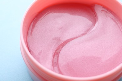 Photo of Under eye patches in jar on light blue background, closeup. Cosmetic product