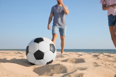 Photo of Friends playing football at beach, focus on ball