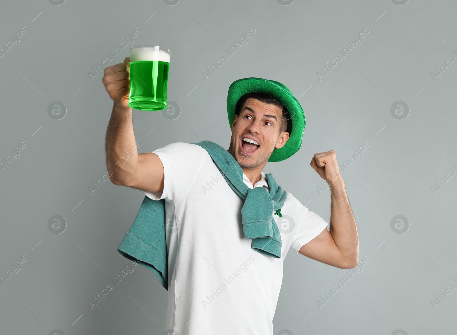 Photo of Emotional man in St Patrick's Day outfit with beer on light grey background