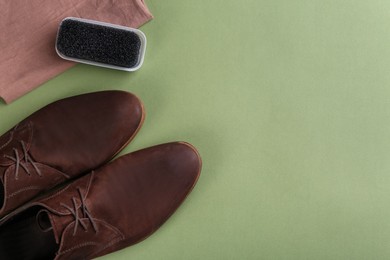 Photo of Stylish footwear with shoe care accessories on green background, flat lay. Space for text