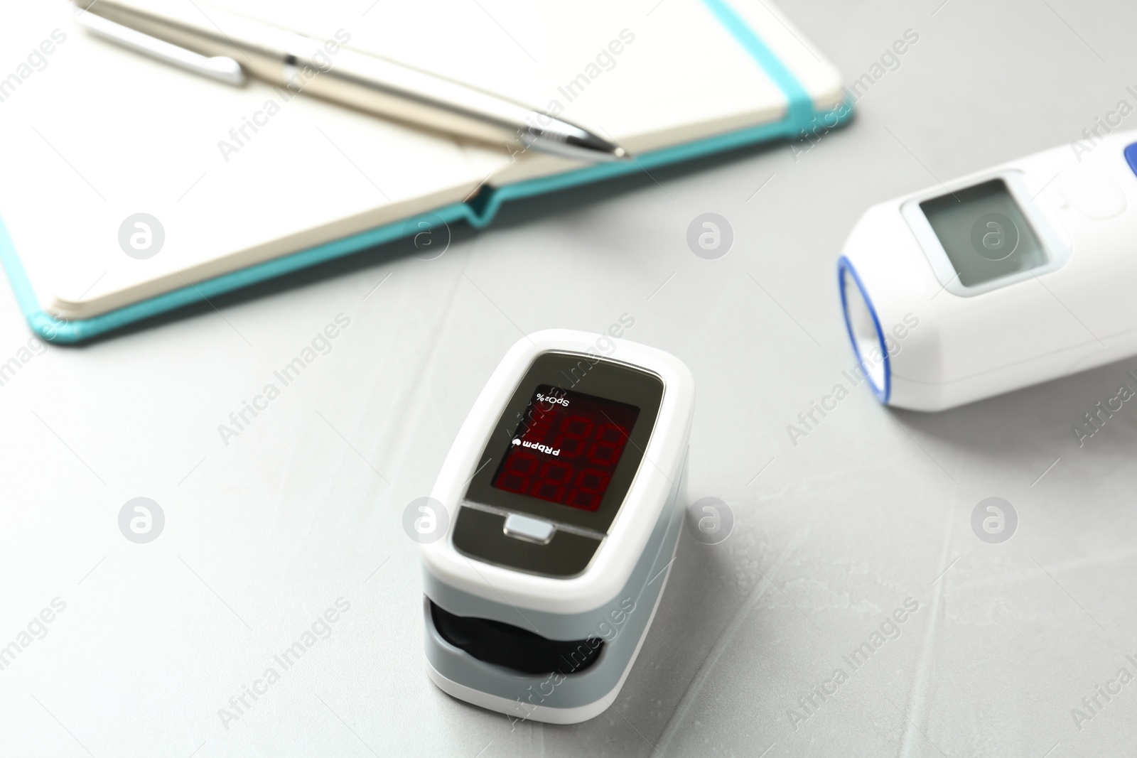 Photo of Modern fingertip pulse oximeter on light grey stone table, closeup