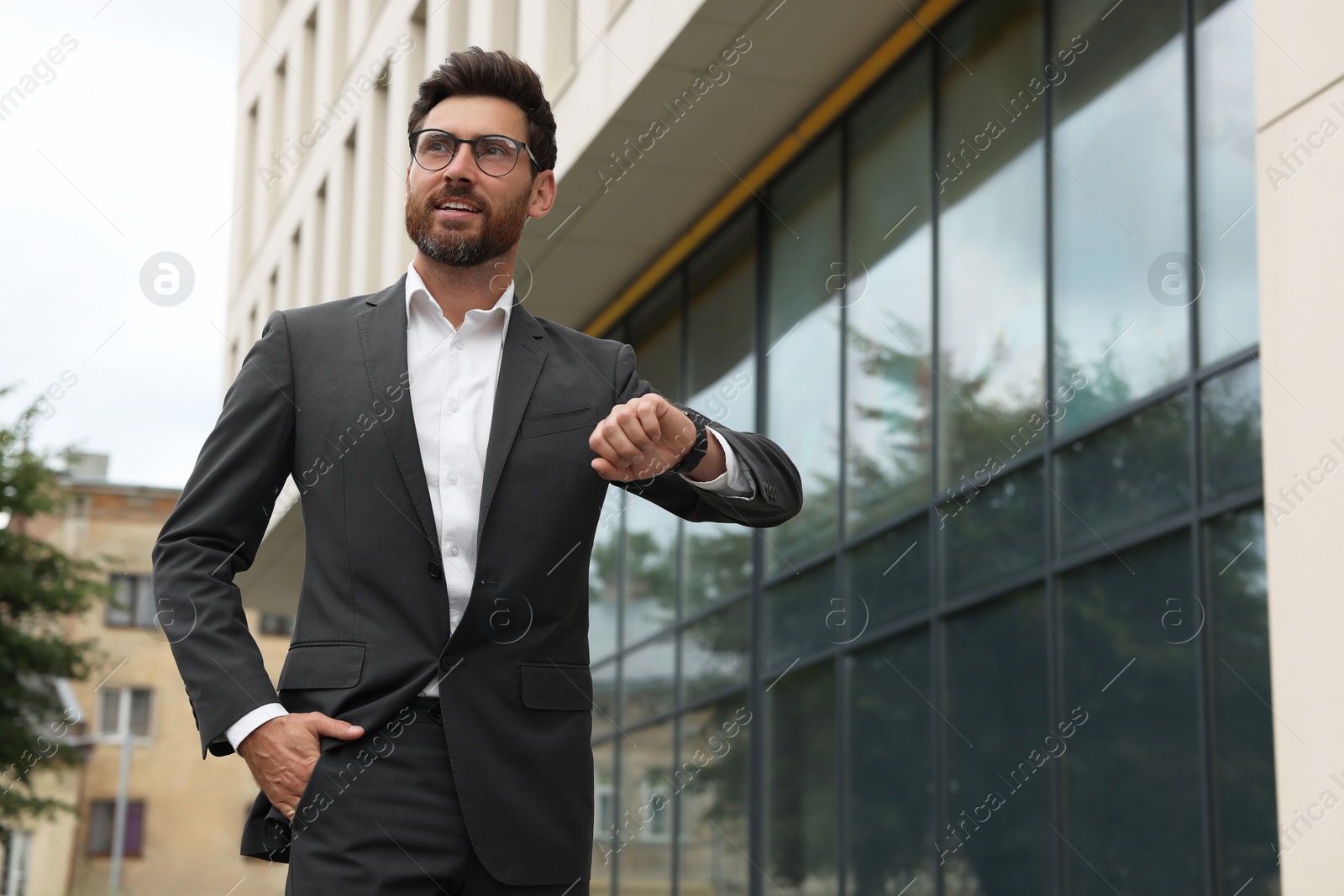 Photo of Handsome bearded businessman in eyeglasses near building outdoors