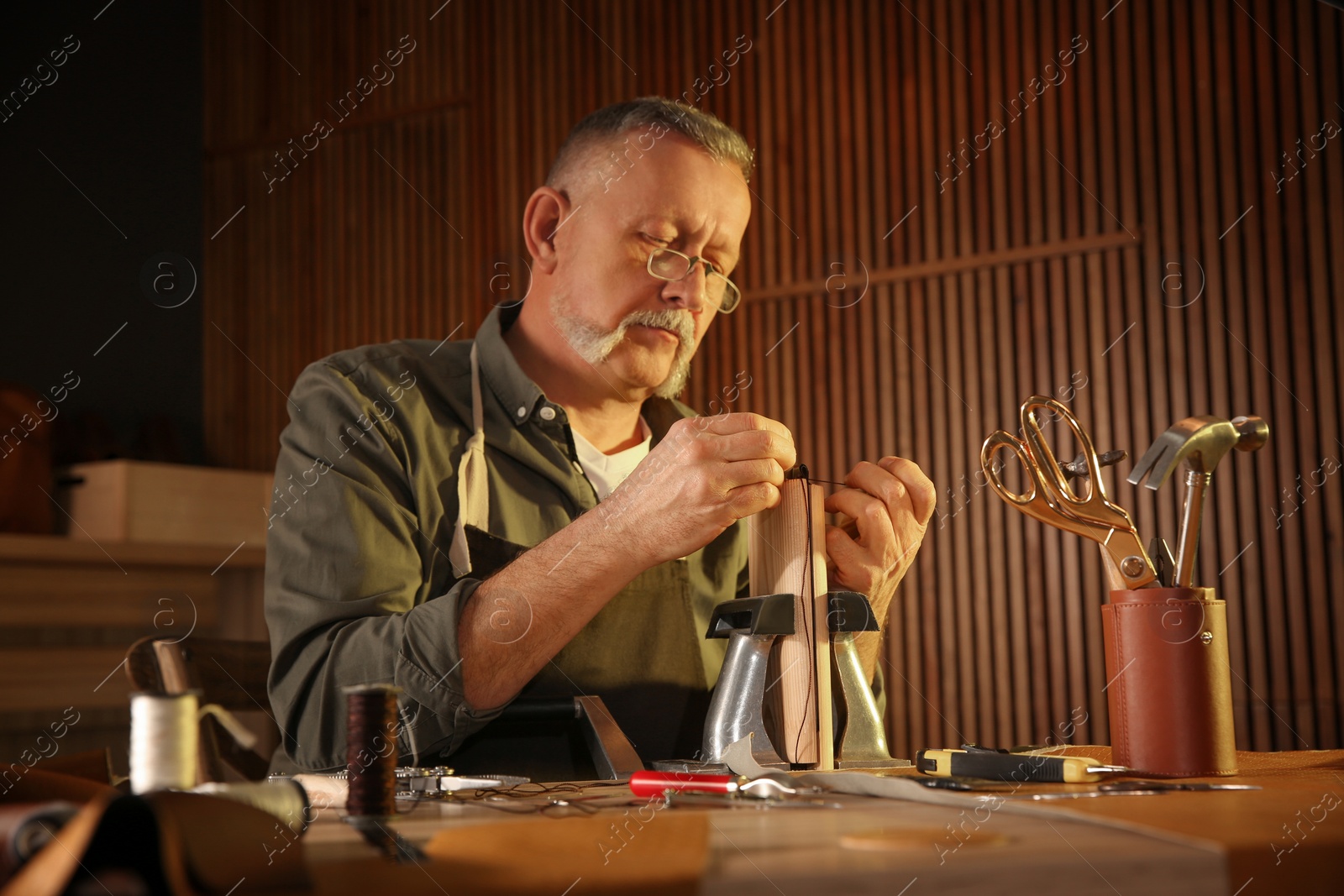 Photo of Man sewing piece of leather in workshop