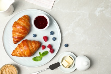 Tasty breakfast with croissants served on light grey marble table, flat lay. Space for text