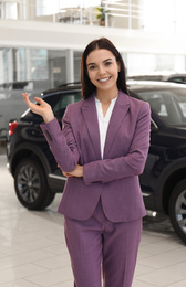 Happy young saleswoman in modern car salon