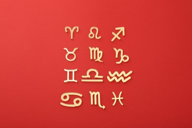 Zodiac signs on red background, flat lay