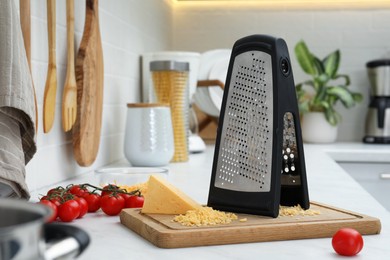 Photo of Grater, cheese and cherry tomatoes on kitchen counter