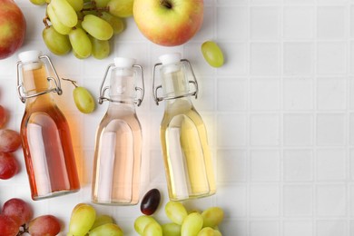 Photo of Different types of vinegar and ingredients on light tiled table, flat lay. Space for text