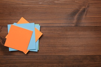 Photo of Stack of colorful stickers on wooden table, top view. Space for text