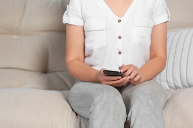 Photo of Woman using smartphone on sofa at home, closeup