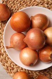 Photo of Many ripe onions on wooden table, flat lay