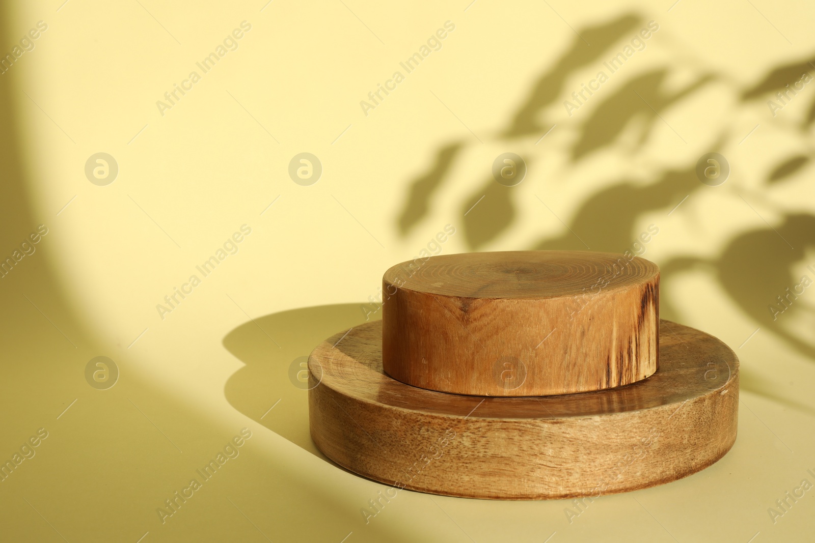 Photo of Presentation of product. Wooden podiums on yellow background. Space for text