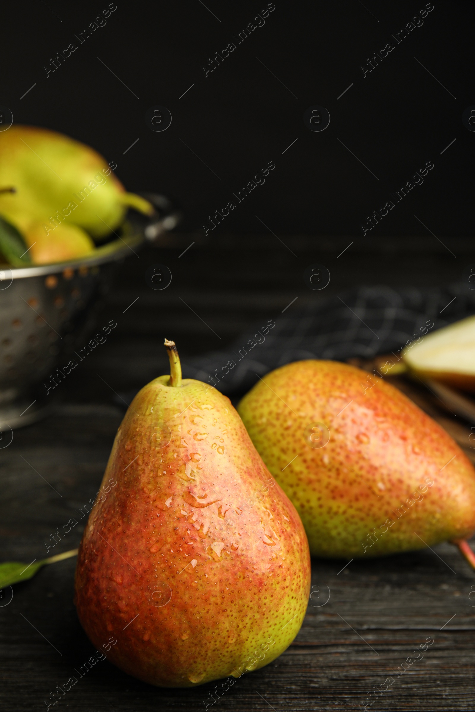 Photo of Ripe juicy pears on dark wooden table against black background. Space for text