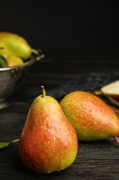 Photo of Ripe juicy pears on dark wooden table against black background. Space for text