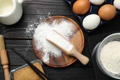 Photo of Flat lay composition with baking powder and products on black wooden table