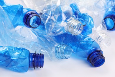 Photo of Crumpled disposable plastic bottles on white background