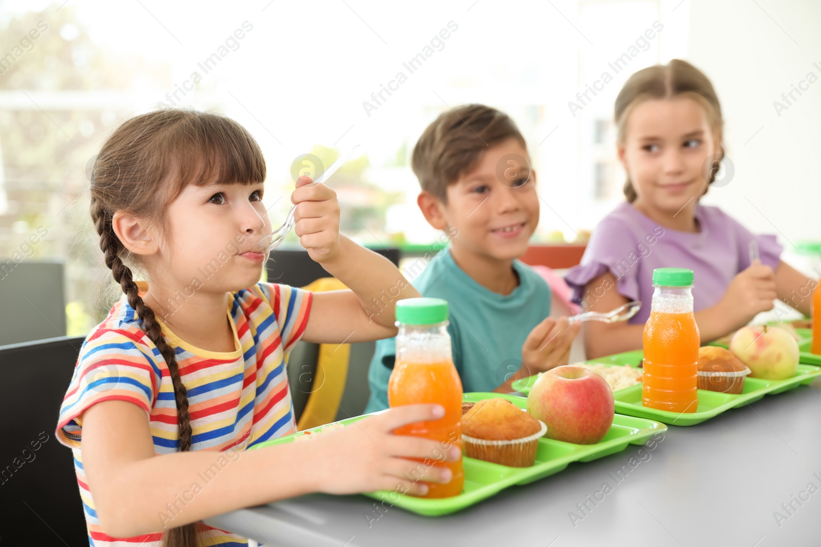 Photo of Children sitting at table and eating healthy food during break at school