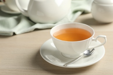 Photo of Cup of hot green tea on wooden table