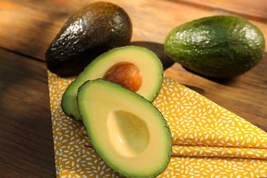 Photo of Fresh whole and cut avocados on wooden table, closeup