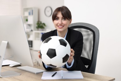 Photo of Smiling employee with soccer ball at table in office