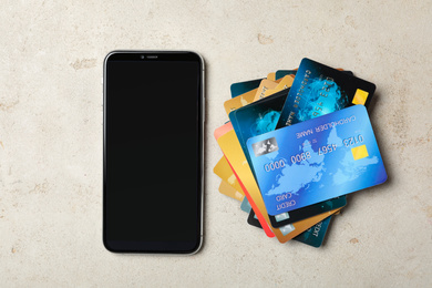 Many different credit cards and smartphone on light background, flat lay. Space for design