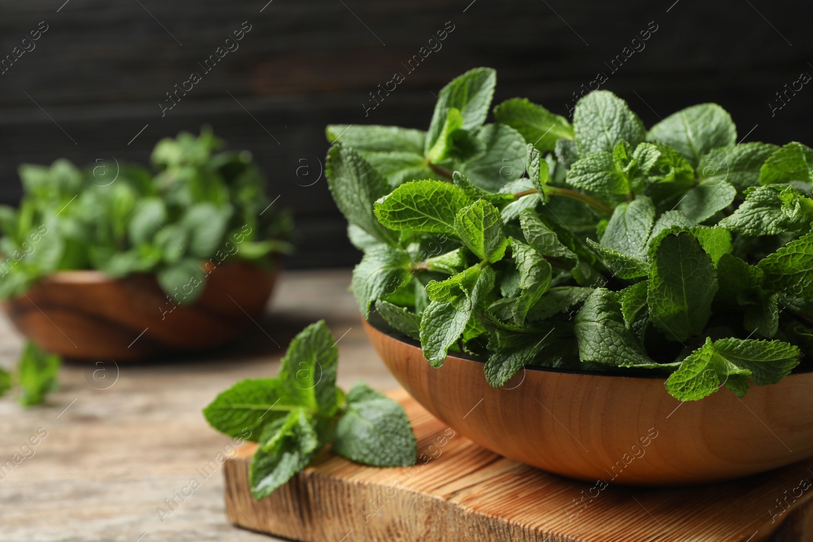 Photo of Board with bowl of fresh green mint on table. Space for text