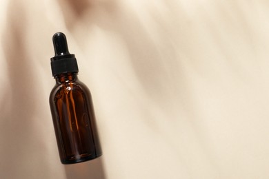 Bottle of cosmetic serum on beige background, top view. Space for text
