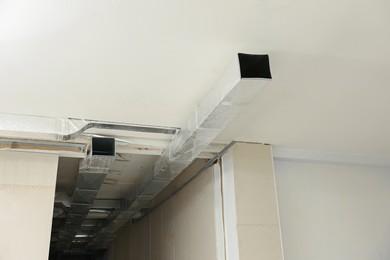 Photo of Modern pipes installed on ceiling indoors. Home renovation