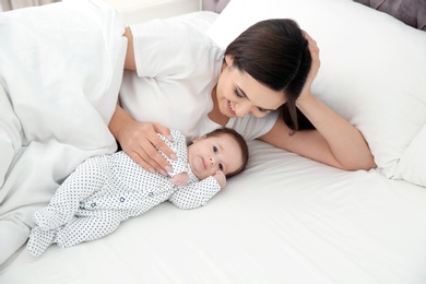 Photo of Happy woman with her cute baby on bed