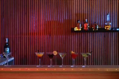 Different martini cocktails on table in bar, space for text